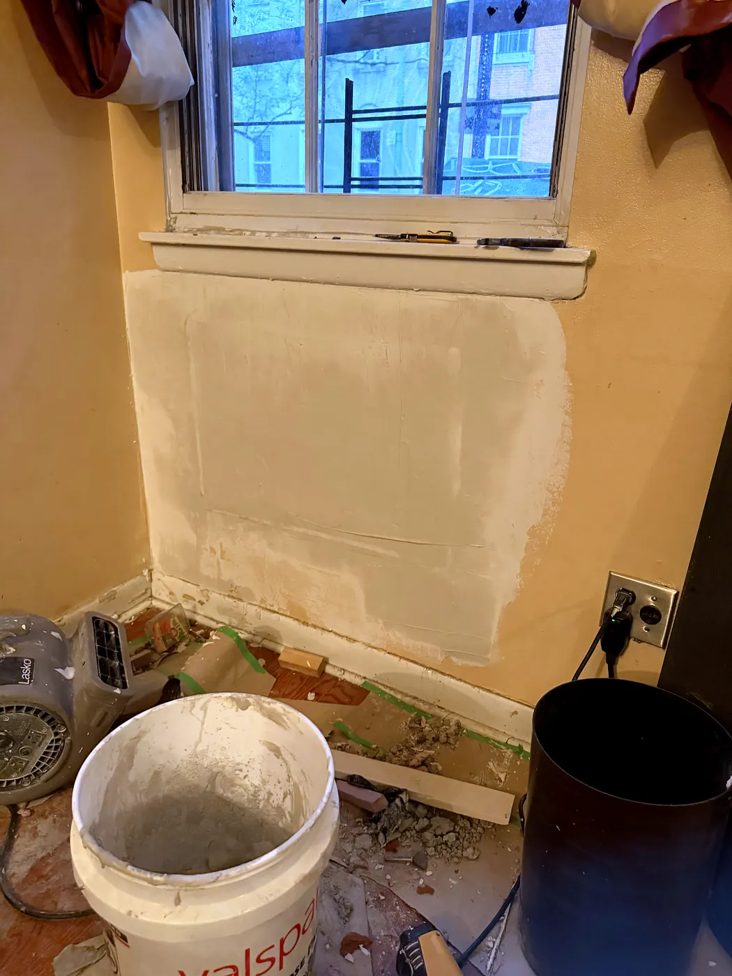 The wall under the window skim-coated with joint compound where the AC was
