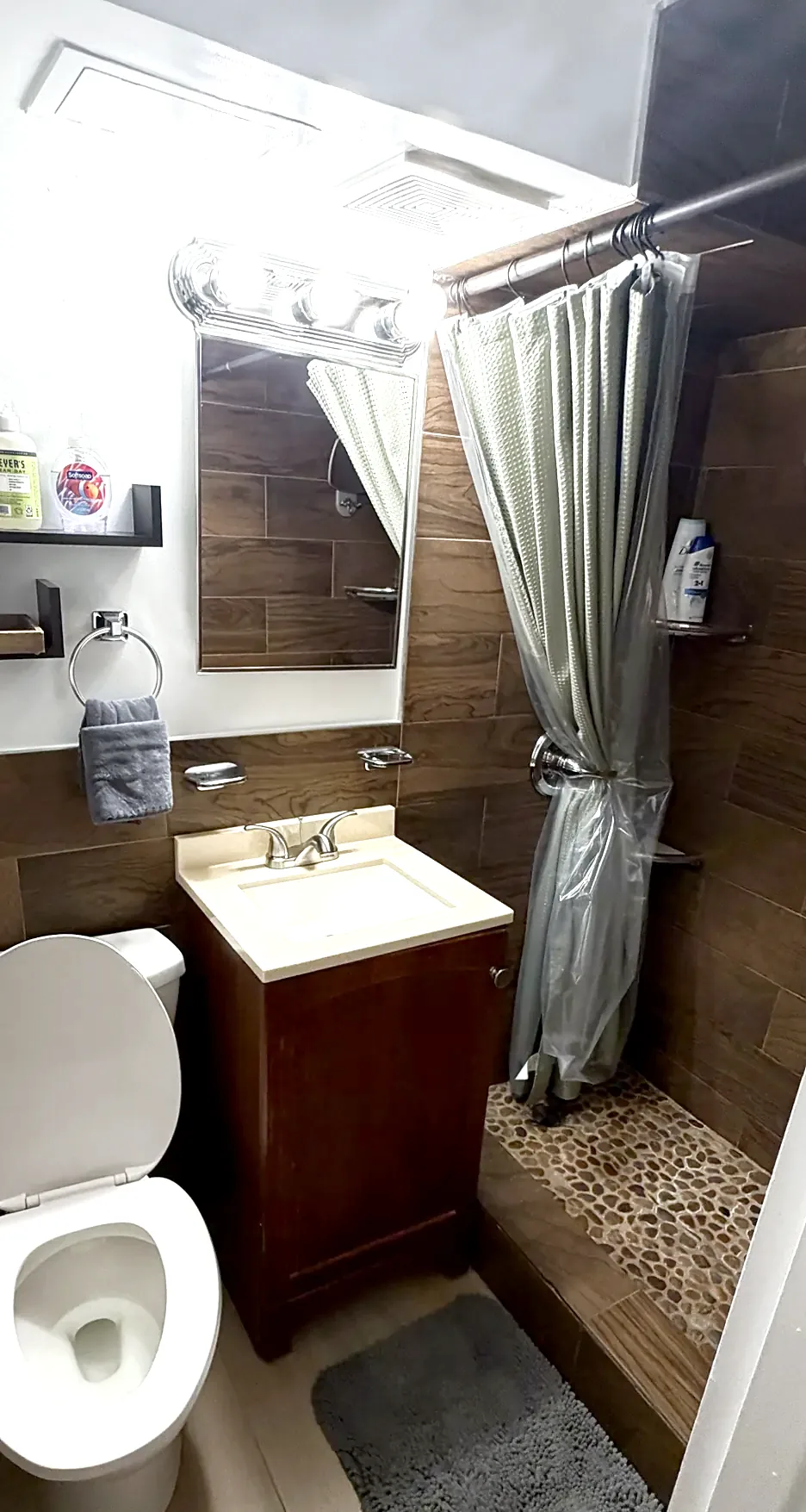 Downstairs bath in 2026: fresh paint, same wood-look tile and river rock shower