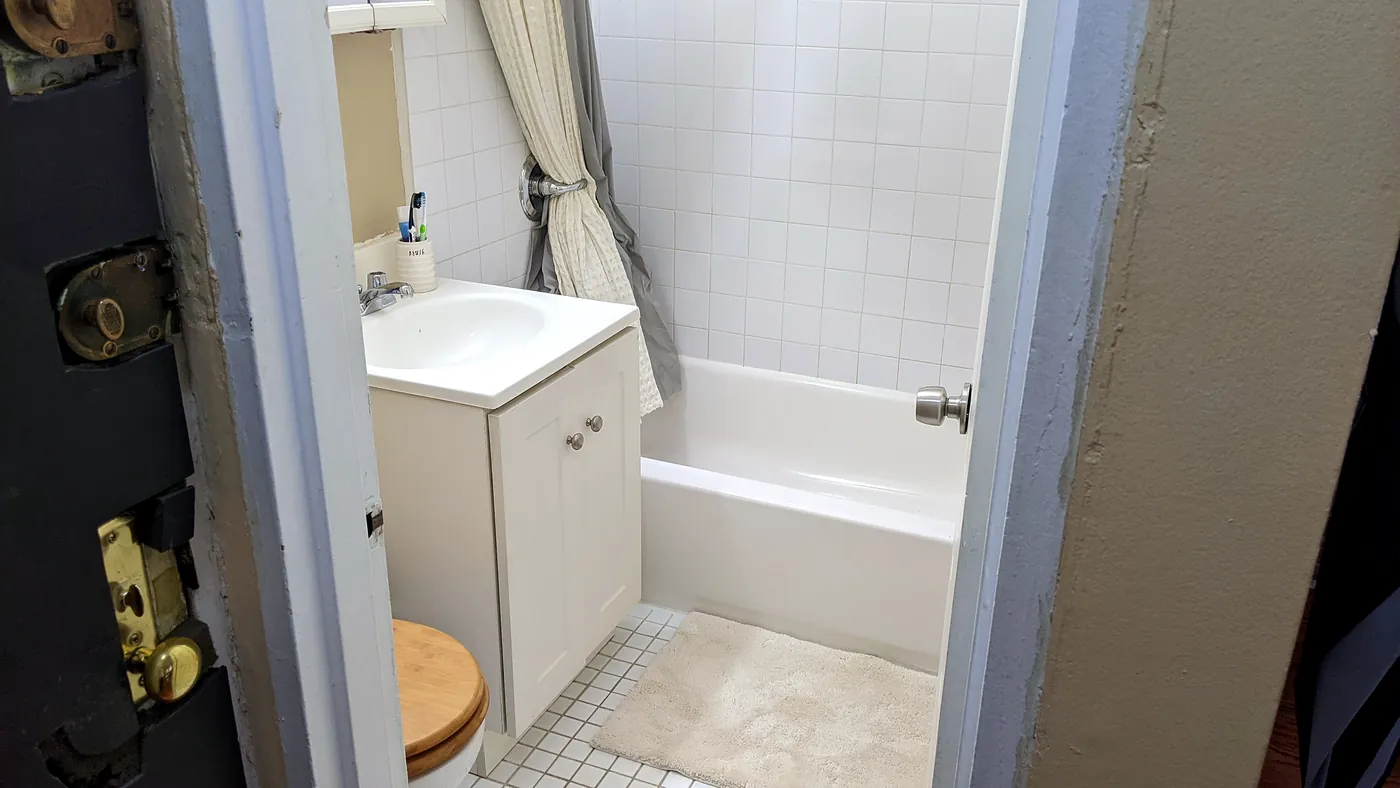 Upstairs bath in 2022: tan walls, white tub, from the doorway