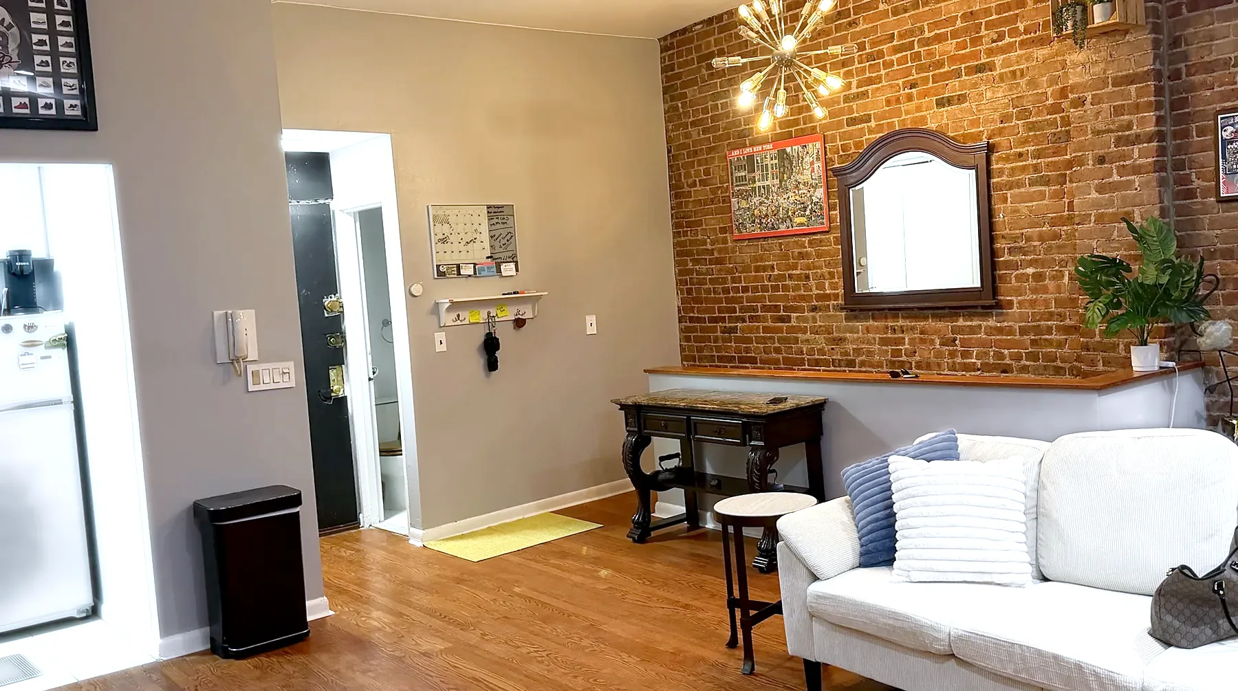 Entry and brick wall in 2026: grey walls, white sofa, cleared brick with sputnik chandelier