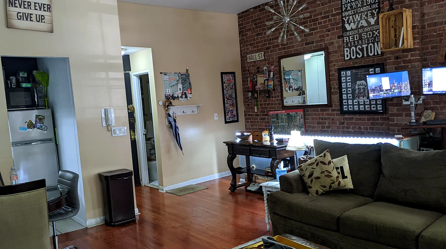 Entry and brick wall in 2022: beige walls, olive sofa, signs and screens on the brick