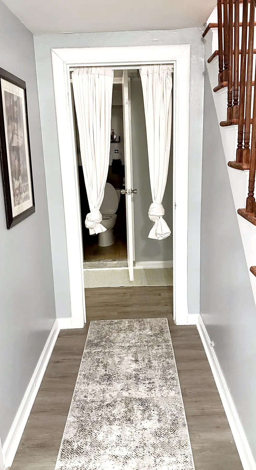 Downstairs hall in 2026: grey walls, patterned runner, stairs on the right