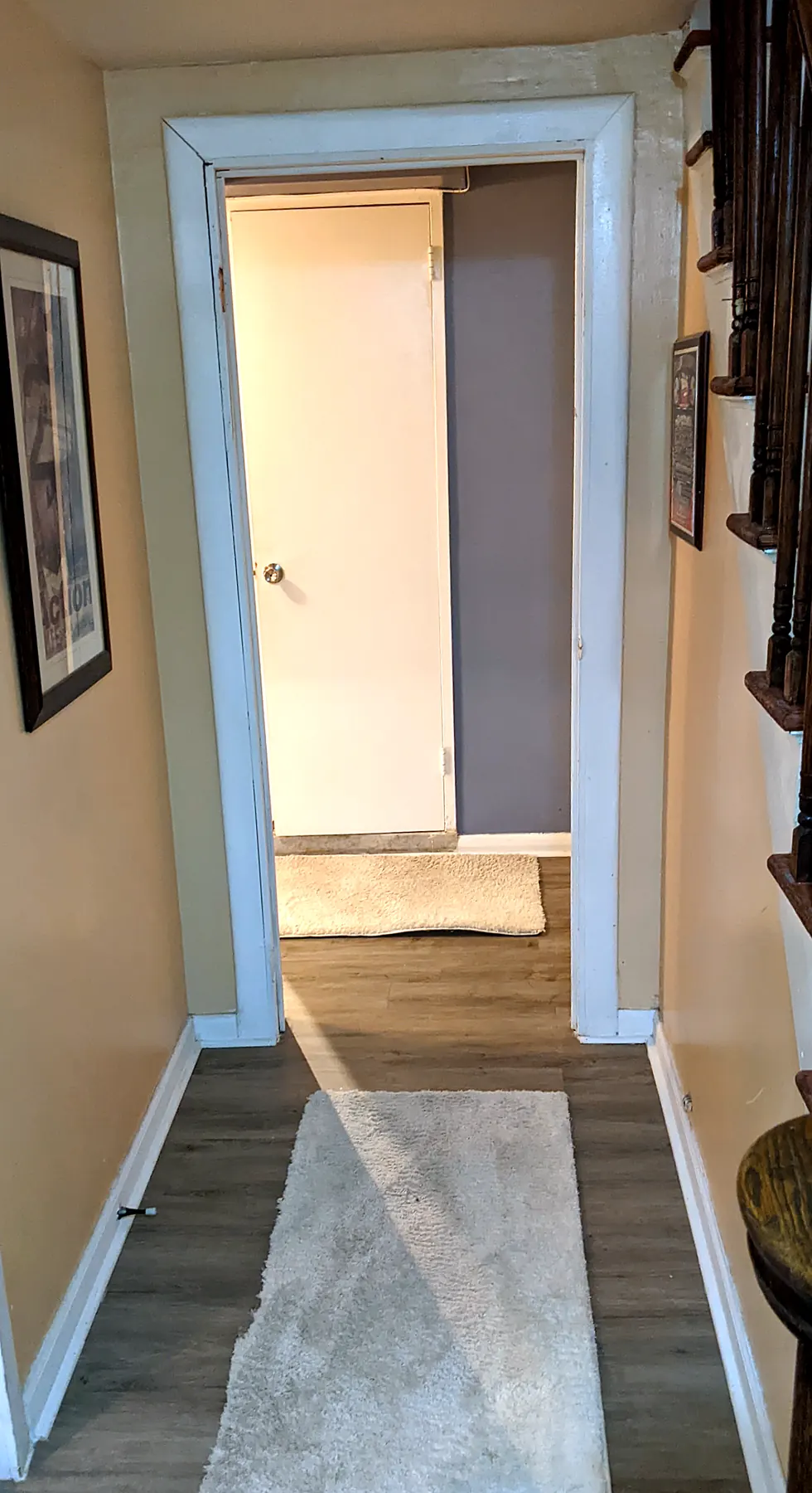 Downstairs hall in 2022: beige walls, white rug, stairs on the right
