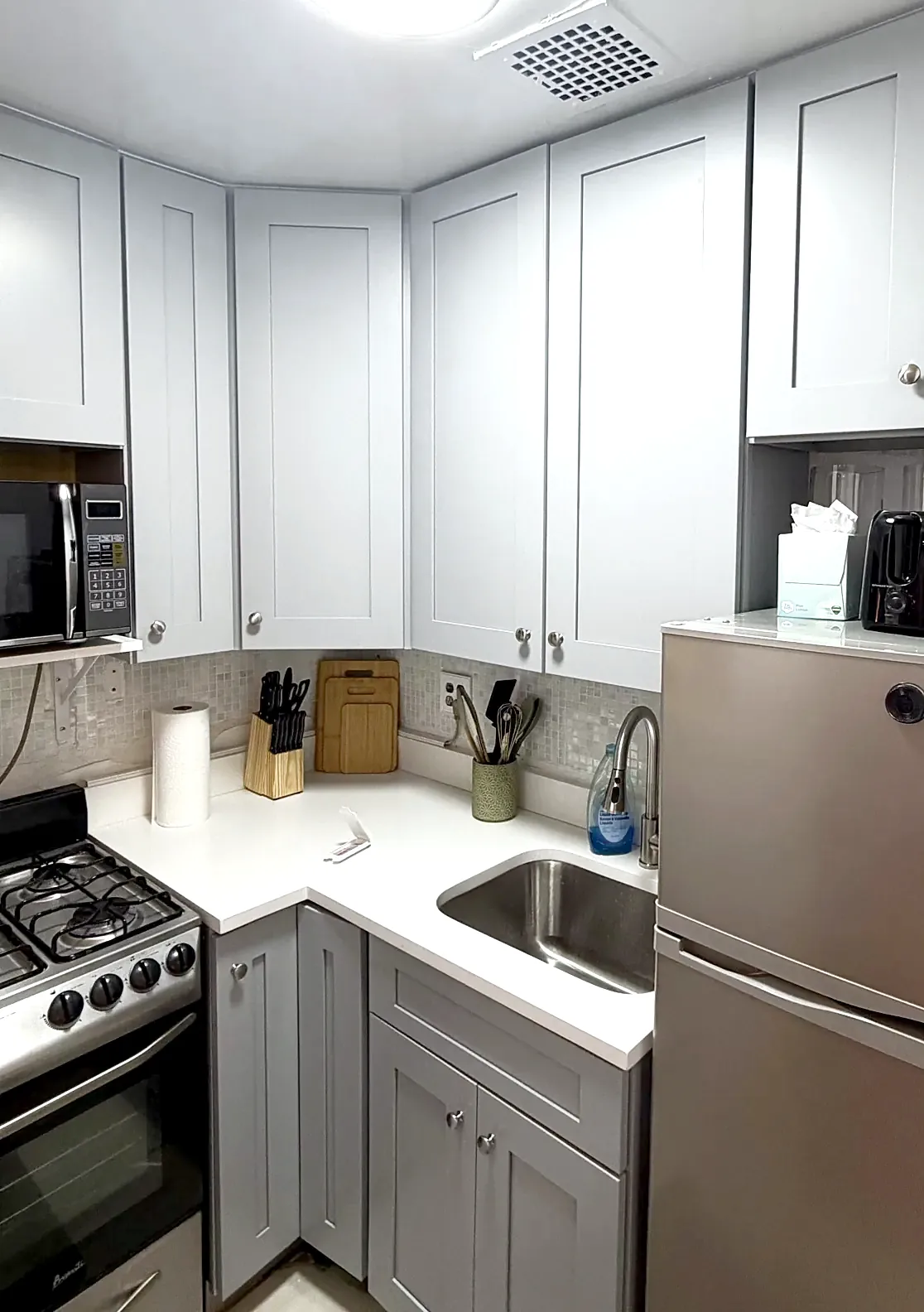Kitchen in September 2026: grey shaker cabinets to the ceiling, white quartz counter, stainless fridge