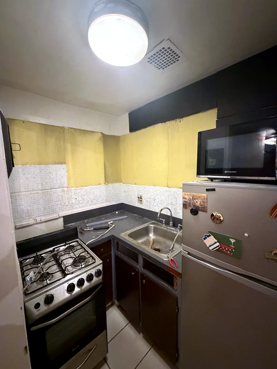 Kitchen on August 27: upper cabinets removed, yellow wall exposed, tools on the counter
