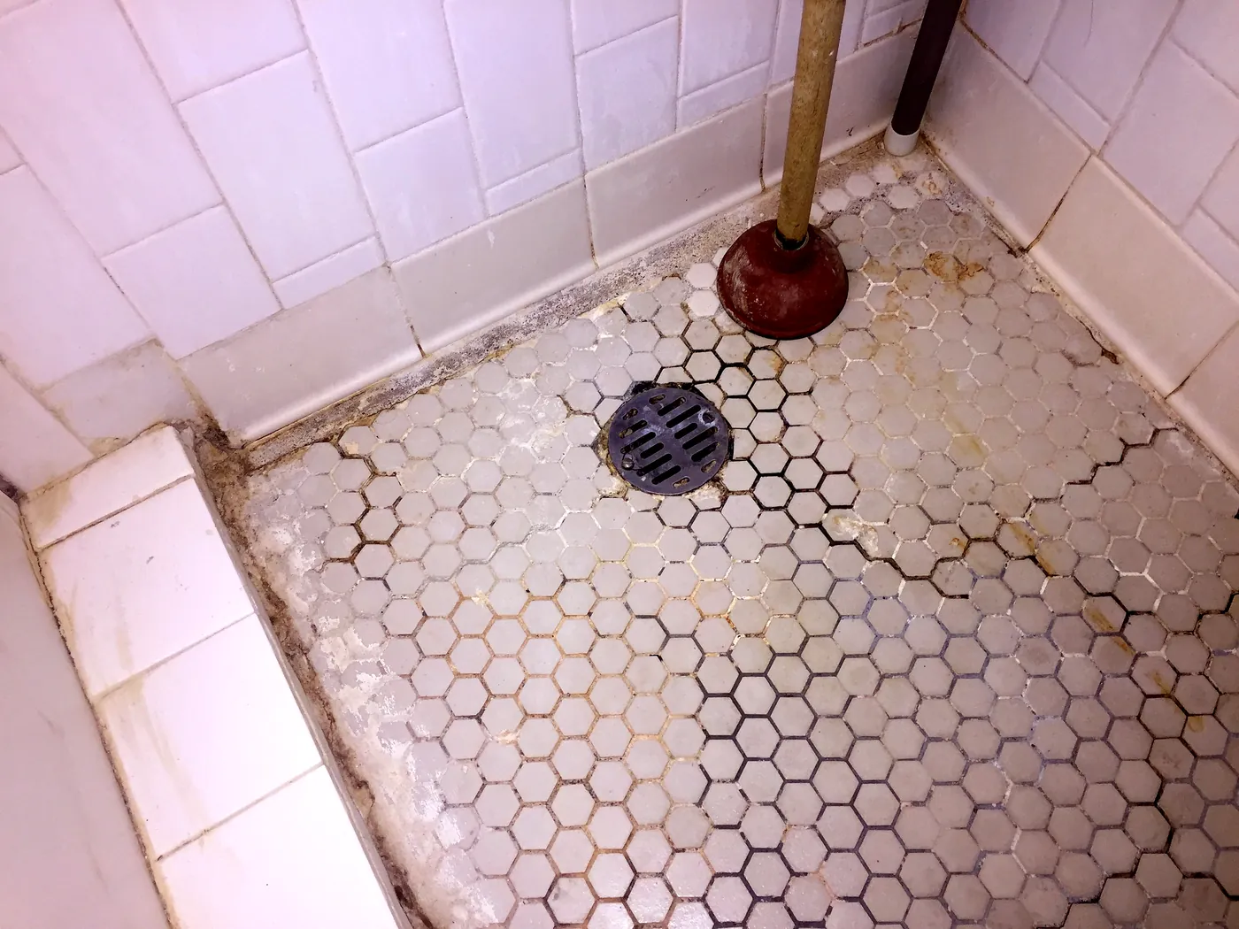 The old shower floor in September 2015: cracked hex tile and stained grout