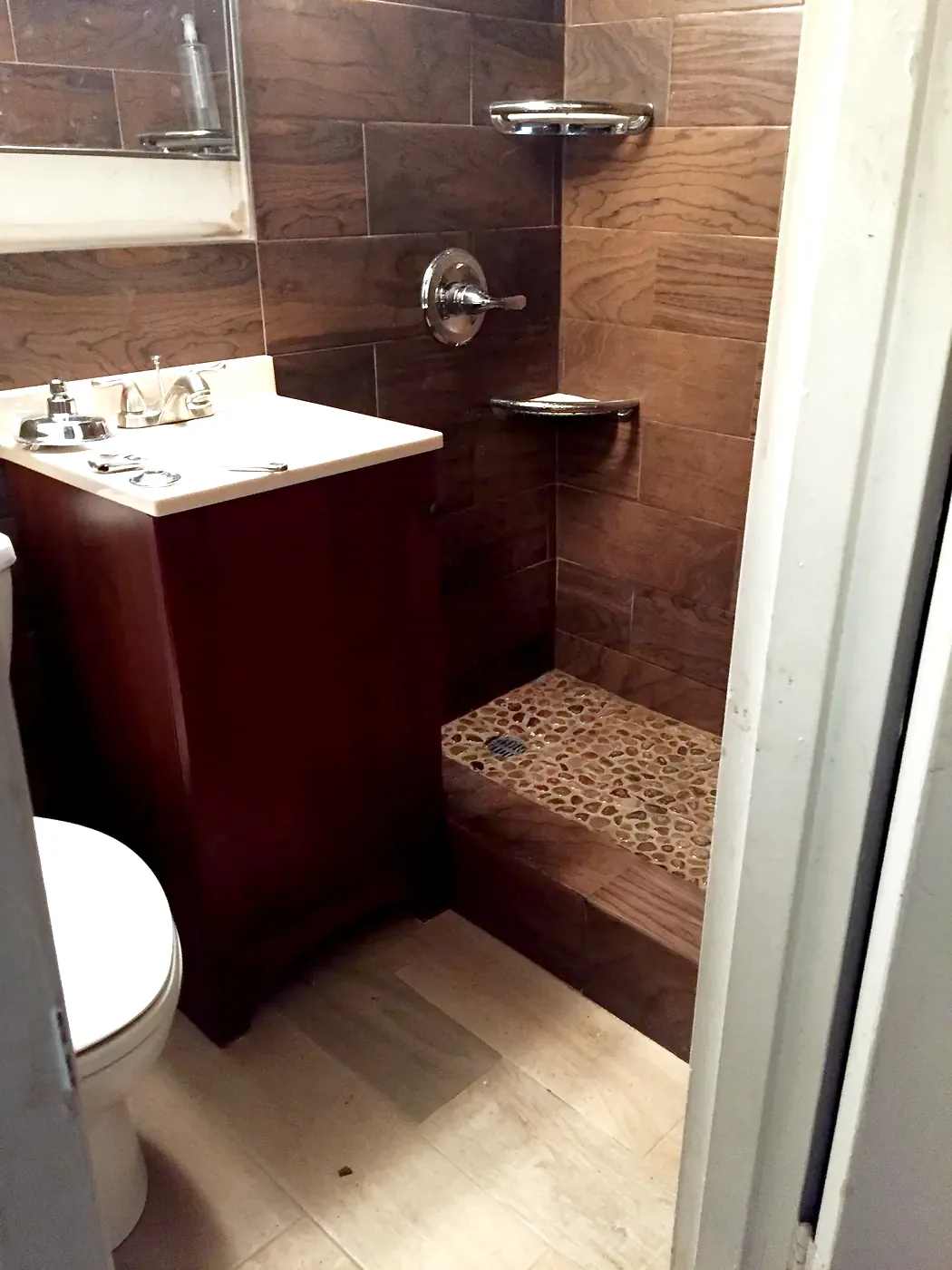 Downstairs bath in January 2016: wood-look tile, dark vanity, river rock shower